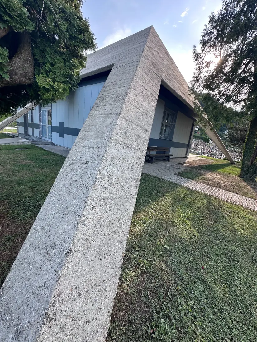 Betonska poševna fasadna površina in stekleni vhod objekta.